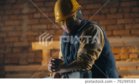 Man drinking hot beverage on construction site Man drinking hot beverage on construction site 76299583