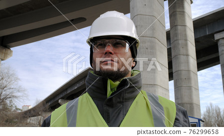 Male contractor looking around under bridge Male contractor looking around under bridge 76299658