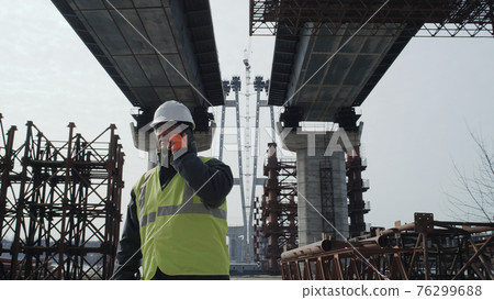 Male engineer walking and talking under bridge 76299688