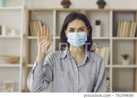 Young caucasian woman remote employee in mask waving hand to camera portrait 76299690