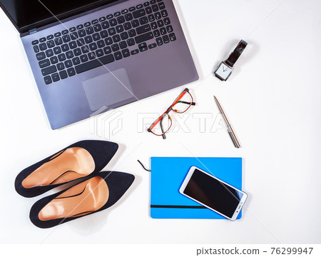 Office kit of businesswoman on the white background. Laptop, notebook, high heels, watches, glasses, smartphone etc. Close-up. Flat lay. Still life. Office kit of businesswoman on the white background. Laptop, notebook, high heels, watches, glasses, smartphone etc. Close-up. Flat lay. Still life. 76299947
