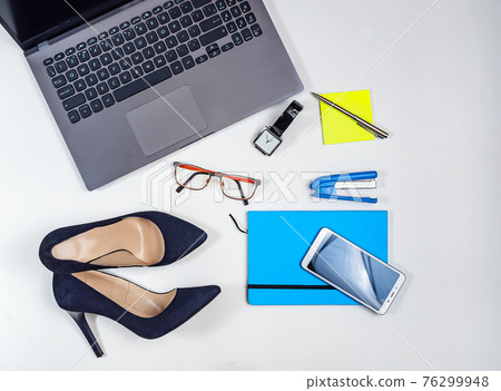 Office kit of businesswoman on the white background. Laptop, notebook, high heels, watches, glasses, smartphone etc. Close-up. Flat lay. Still life. 76299948