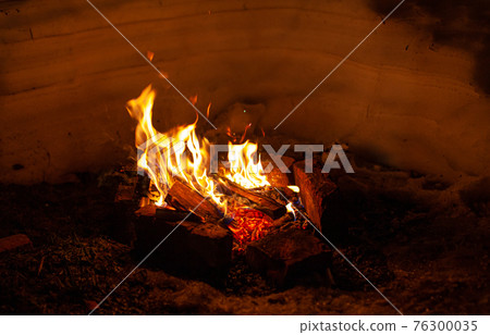 A campfire burns in the snow at night in the snow in the cold winter A campfire burns in the snow at night in the snow in the cold winter 76300035