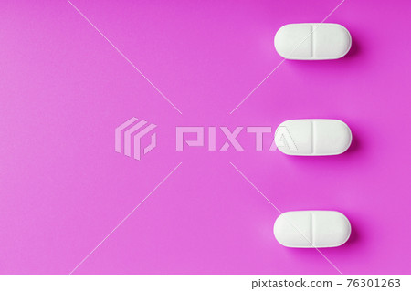 White Ecstasy pills in a row on a pink background, isolate. White Ecstasy pills in a row on a pink background, isolate. 76301263