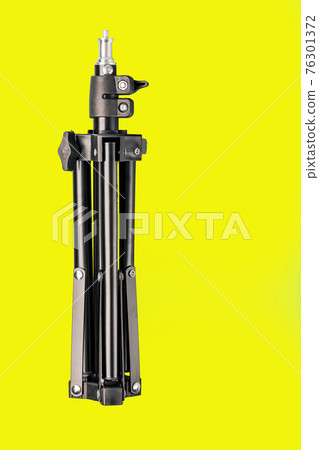 Folding tripod for cameras and smartphones on a yellow background. 76301372