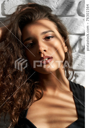 Brunette girl posing near white brick wall. Brunette girl posing near white brick wall. 76301564