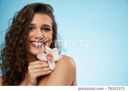 Smiling woman holding flower, isolated on blue. Smiling woman holding flower, isolated on blue. 76301571