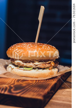 Close Up of Burger Piled High with Fresh Toppings on Whole Grain Artisan Bun, on Rustic Wooden Surface with Dark Background and Copy Space. 76301684