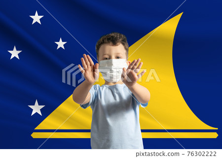 Little white boy in a protective mask on the background of the flag of Tokelau. Makes a stop sign with his hands, stay at home Tokelau Little white boy in a protective mask on the background of the flag of Tokelau. Makes a stop sign with his hands, stay at home Tokelau 76302222