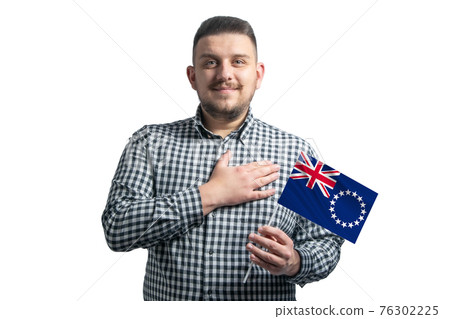 White guy holding a flag of Cook Islands and holds his hand on his heart isolated on a white background With love to Cook Islands White guy holding a flag of Cook Islands and holds his hand on his heart isolated on a white background With love to Cook Islands 76302225