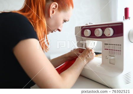 Portrait of dressmaker woman working on white sewing machine Portrait of dressmaker woman working on white sewing machine 76302521