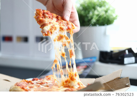 Hand takes a piece of delicious hot pizza closeup Hand takes a piece of delicious hot pizza closeup 76302523