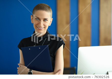 Beautiful woman holds a folder in the workplace Beautiful woman holds a folder in the workplace 76302526