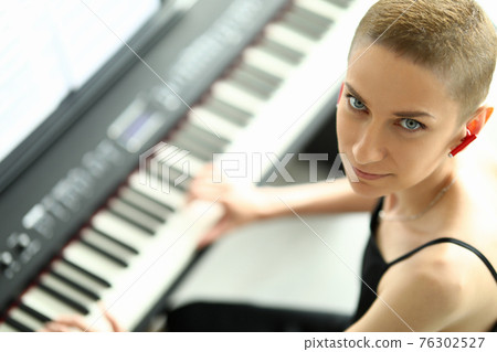 Woman plays electronic music with a headset her ear Woman plays electronic music with a headset her ear 76302527