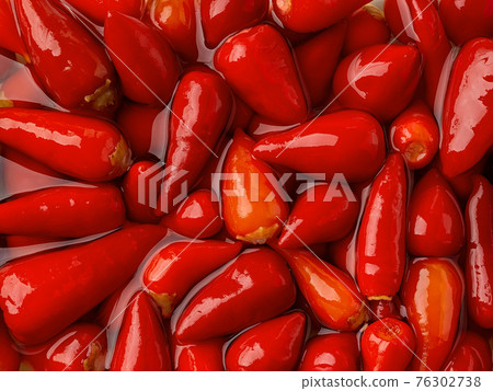 Pickled baby red hot peppers in a marinade as a background. Pickled baby red hot peppers in a marinade as a background. 76302738