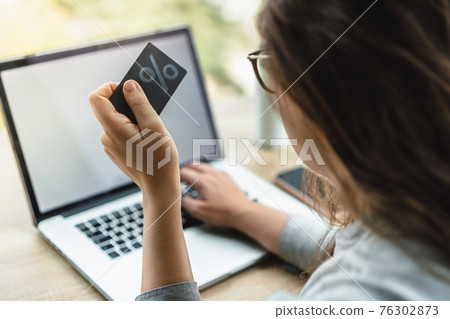 Woman shopping online with laptop holding a credit card Woman shopping online with laptop holding a credit card 76302873