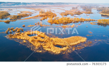 Overflow water at springtime. Rural sunrise landscape. Meadows covered by water. Overflow water at springtime. Rural sunrise landscape. Meadows covered by water. 76303173