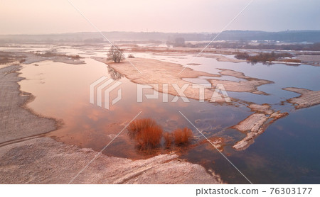Sunrise spring melting river flood aerial panorama. Overflow water at springtime. Rural April landscape. 76303177
