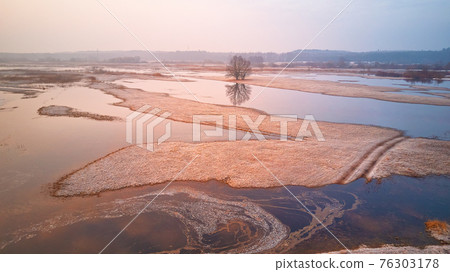 Sunrise spring melting river flood aerial panorama. Overflow water at springtime. Rural April landscape. Sunrise spring melting river flood aerial panorama. Overflow water at springtime. Rural April landscape. 76303178