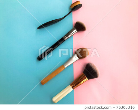 Beautiful fashionable beauty glamorous white and gold brushes and brushes for applying makeup and powder on the face on a blue-pink gentle background. Flat lay Beautiful fashionable beauty glamorous white and gold brushes and brushes for applying makeup and powder on the face on a blue-pink gentle background. Flat lay 76303316