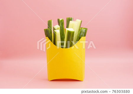 Healthy food, fast food abstract concept. Fresh cucumber stick in yellow papper bag on pink background. 76303880