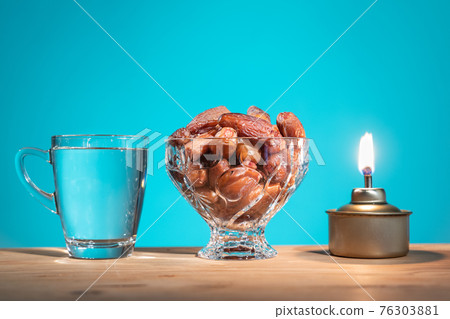 Muslim iftar of breaking of fast food during Ramadan month with preserved sweet dates and water. Pelita oil lamp as prop. Muslim iftar of breaking of fast food during Ramadan month with preserved sweet dates and water. Pelita oil lamp as prop. 76303881