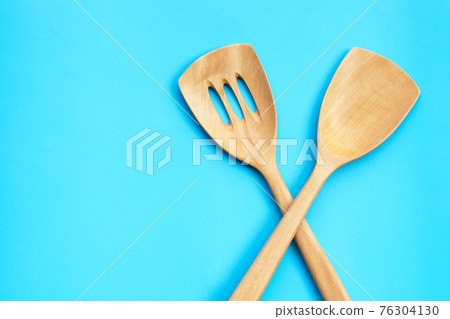 Wooden kitchen spatula on blue background. 76304130
