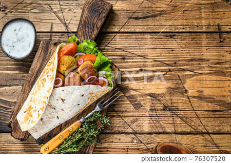 Vegetarian Tortilla wrap with falafel and fresh salad, vegan tacos. wooden background. Top view. Copy space 76307520