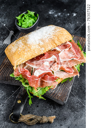 iberico jamon ham sandwich on ciabatta bread. Black background. Top view iberico jamon ham sandwich on ciabatta bread. Black background. Top view 76307522