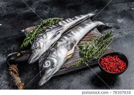 Raw icefish on a wooden cutting board. Black background. Top view Raw icefish on a wooden cutting board. Black background. Top view 76307638