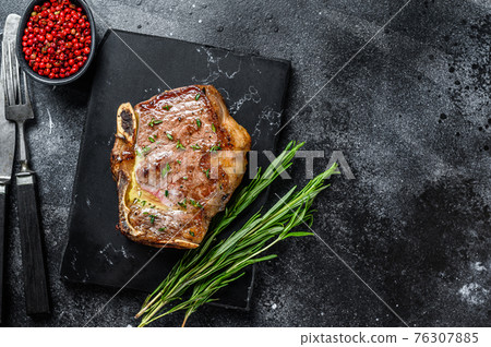 Grilled striploin steak on the bone or new york steak. Black background. Top view. Copy space 76307885