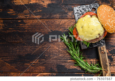 Grilled homemade burger with beef, tomato, cheese, cucumber and lettuce on a meat cleaver. Dark wooden background. Top view. Copy space Grilled homemade burger with beef, tomato, cheese, cucumber and lettuce on a meat cleaver. Dark wooden background. Top view. Copy space 76307887