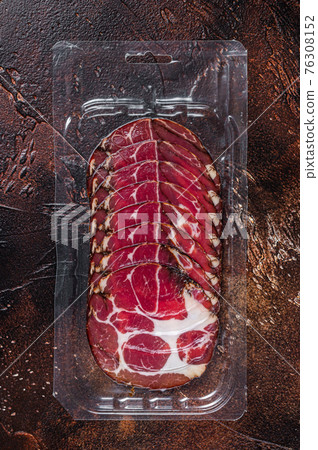Italian sliced cured coppa meat in vacuum packaging. Dark background. Top view Italian sliced cured coppa meat in vacuum packaging. Dark background. Top view 76308152
