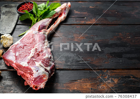 Whole raw goat leg with herbs and spices. Farm meat. Dark wooden background. Top view. Copy space 76308437