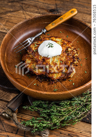Roasted Potato pancakes or Fritters with herbs in a wooden plate. wooden background. Top view Roasted Potato pancakes or Fritters with herbs in a wooden plate. wooden background. Top view 76308515