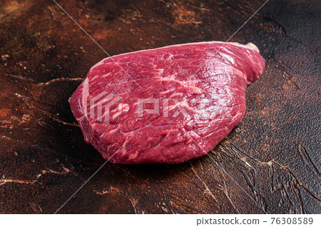 Raw rump beef cut or top sirloin meat steak on butcher table. Dark background. Top view 76308589