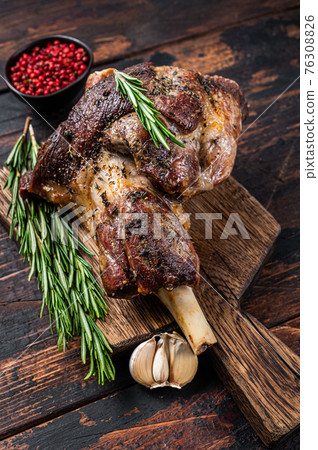Baked lamb mutton leg meat on a wooden cutting board. Dark wooden background. Top view Baked lamb mutton leg meat on a wooden cutting board. Dark wooden background. Top view 76308826