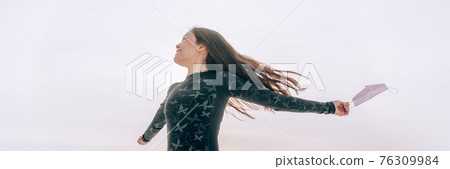 Coronavirus happy woman dancing outside in freedom with open arms letting go of face mask. Pandemic crisis is over, vaccine is coming banner concept 76309984