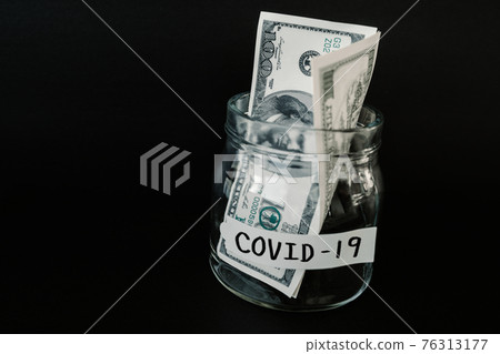 Economy during coronavirus pandemic concept. Saving money in jar on black background. 76313177