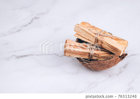 Palo Santo tree sticks inside coconut shell on marble background - holy incense tree from Latin America. Meditation, mental health and personal fulfilment concept. Selective focus Palo Santo tree sticks inside coconut shell on marble background - holy incense tree from Latin America. Meditation, mental health and personal fulfilment concept. Selective focus 76313248