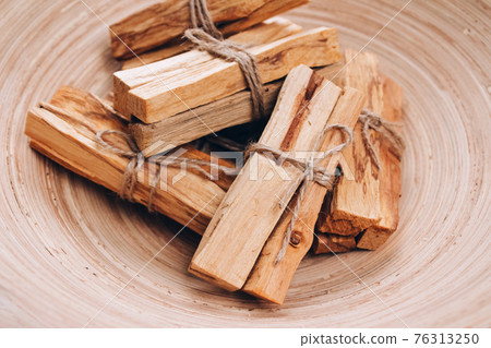 Palo Santo tree sticks in wooden bowl - holy incense tree from Latin America. Meditation, mental health and personal fulfilment concept. Selective focus 76313250