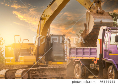 Backhoe working by digging soil at construction site and loading to the truck. Bucket of backhoe transport soil to truck. Crawler excavator dump dirt soil to heavy dump truck. Excavating machine. 76314543