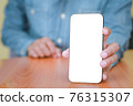 The man is handing out a white mobile phone screen to the front. 76315307