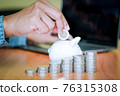 Businessmen put the coins into the white piggy bank and the coins stacks 76315308
