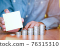 A businessman holding a blank note with coins stack placed on the front 76315310
