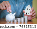 Businessmen put the coins into the white piggy bank and the coins stacks 76315313