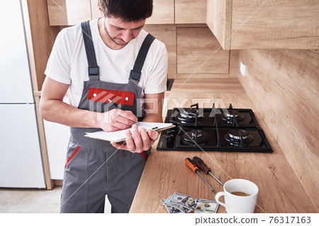 Plumber signs a contract for the services in the kitchen Plumber signs a contract for the services in the kitchen 76317163
