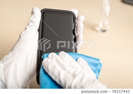 Hand cleaning smartphone screen with alcohol 76317443