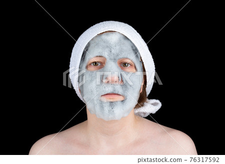 Young woman with cosmetic bubble mask with charcoal on her face. Young woman with cosmetic bubble mask with charcoal on her face. 76317592