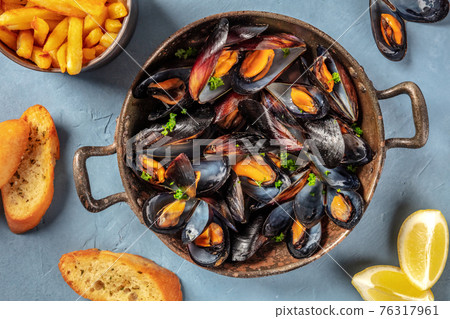 Mussels in a pan, with French fries, toasted bread, and lemon Mussels in a pan, with French fries, toasted bread, and lemon 76317961